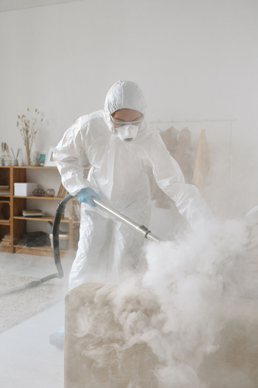 Specialist cleaner using decontamination equipment while wearing full PPE